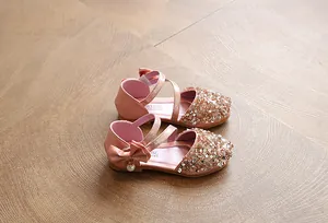 Close-up detail of pink children's dress shoes featuring sequins and a side bow