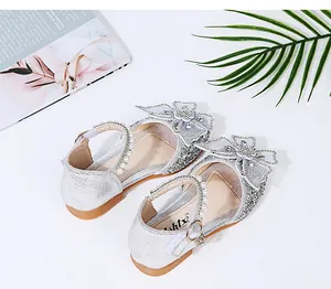 Detail view of sparkling silver girl's princess shoes with bows and pearls