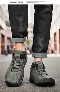 Close-up of men's green leather casual shoes with manual stitching on an urban street.