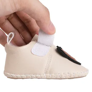 Detailansicht des verstellbaren Klettverschlusses an cremefarbenen Baby-Lauflernschuhen
