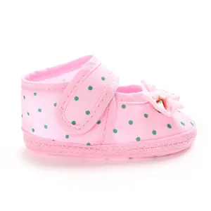 Side view of pink baby shoe with green polka dots and bow detail