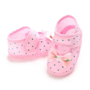 Close-up detail of pink polka dot baby shoes featuring decorative bow and soft anti-slip sole
