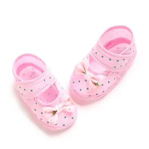Macro detail of soft pink baby shoes featuring green polka dots and pink bows