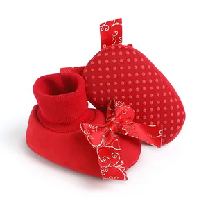 Detailed view of festive red baby walking shoes with large bow and non-slip dotted soles