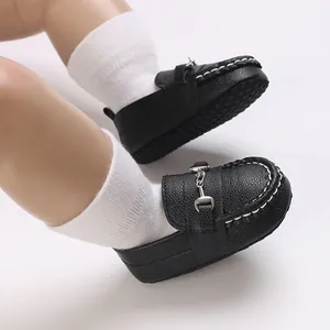 Détails rapprochés de mocassins noirs pour bébé avec boucle en métal et coutures