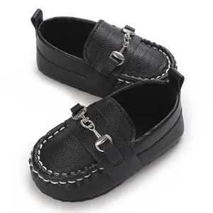 Détail de mocassins en cuir noir pour bébé avec coutures blanches et mors métallique