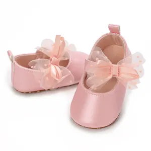 Vista detallada de zapatos rosas para bebé con lazo grande de malla y piel suave