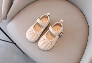 Dettaglio di scarpe Mary Jane color crema per bambine con punta a pieghe e cinturino