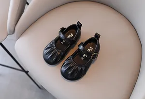 Dettaglio di scarpe Mary Jane nere da bambina con punta a pieghe e cinturino.