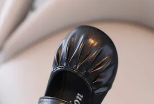Primo piano di scarpa in pelle nera a pieghe per bambina che mostra la trama del materiale