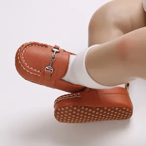 Détail de mocassins pour bébé en cuir marron avec boucle en métal et semelle souple antidérapante