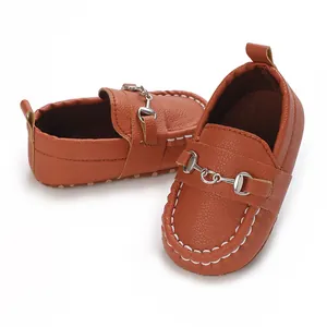 Détail de mocassins marron pour bébé en similicuir avec mors de cheval argenté classique