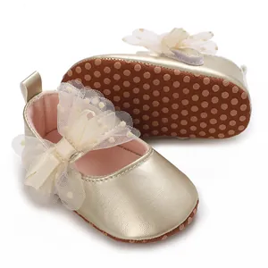 Detalle de zapatos de princesa dorados para bebé con lazo de malla y suela antideslizante.
