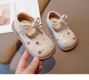 Detailed view of toddler girls' beige leather shoes with floral embroidery and bow strap