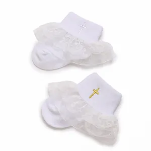 Detail view of white baby socks featuring delicate lace ruffles and cross embroidery