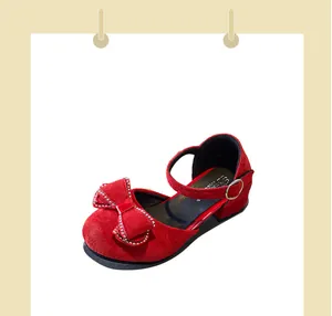 Detalle de zapatos rojos con tacón para niña con un gran lazo de pedrería y correa