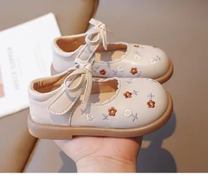 Close-up of beige children's Mary Jane shoes with floral embroidery and bow