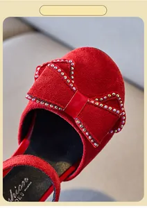 Detalle de zapatos de princesa en ante rojo para niña con un lazo de diamantes finos