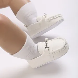 Vue détaillée de mocassins blancs pour bébé avec mors en métal argenté et semelles souples.