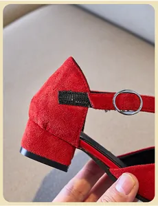 Detalle del tacón y la hebilla de un zapato de tacón para niña en ante rojo vibrante