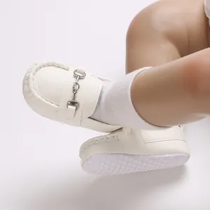 Gros plan de mocassins blancs pour bébé avec mors en métal et semelle souple antidérapante