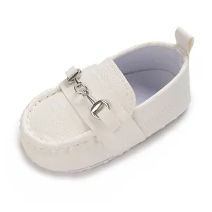 Gros plan sur un mocassin blanc pour bébé avec détail mors métallique et semelle souple