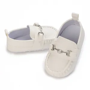 Gros plan sur les mocassins blancs pour bébé avec semelle souple et boucle en métal argenté