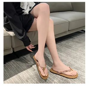 Modelo con chanclas planas de mujer con estampado bohemio sobre una alfombra gris