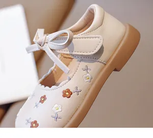 Detailed view of beige toddler Mary Jane shoes featuring delicate floral embroidery and a bow