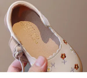 Detail view of floral embroidery and golden branding on toddler girl's beige flats