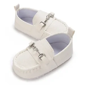 Gros plan de mocassins blancs pour bébé avec boucle argentée et une semelle souple