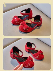 Detalle de zapatos de princesa rojos para niña con lazo de strass y acabado aterciopelado.