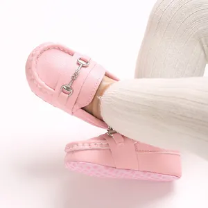 Gros plan de mocassins roses pour bébés à semelle souple avec boucle métallique pour bébés