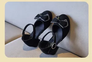 Detalle de zapatos negros para niña con lazo de pedrería brillante y elegante textura de ante