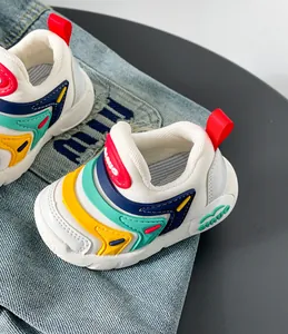 Makro-Detailansicht bunter Raupen-Lernlaufschuhe für Kleinkinder auf Jeans-Hintergrund.