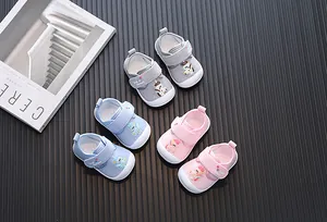 Set of three pairs of cartoon baby walking shoes in grey, blue, and pink for toddler steps