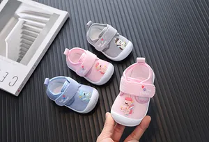 Close-up of pink corduroy baby walking shoes featuring a cartoon unicorn design