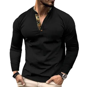 Detail of the waffle texture and contrast printed collar on a black men's polo shirt.