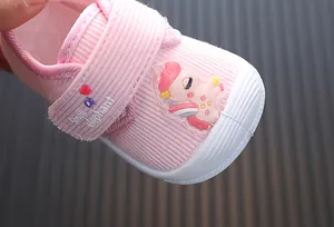 Close-up of pink toddler walking shoe with cute cartoon patch and velcro strap.