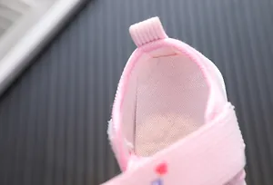 Close-up showing the soft breathable textile inner lining and heel pull tab of pink baby shoes.