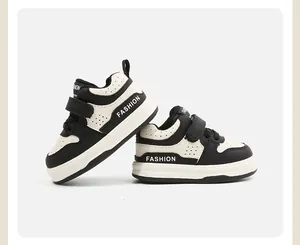 Vista lateral detallada de zapatillas blancas y negras para niños con texto y cierre velcro