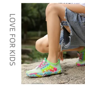 Kind draagt kleurrijke sneldrogende waterschoenen op een rots in een zonnig buitenpark