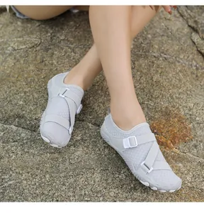 Lightweight grey non-slip water shoes for swimming and snorkeling shown on a rocky beach.