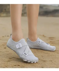 Close-up detail of grey non-slip outdoor water shoes with cross straps on a beach background