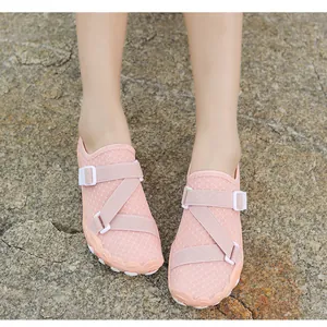 Close-up view of pink mesh swimming wading shoes with adjustable straps on rock