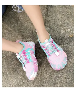 Dichtbijbeeld van roze en blauwe waterschoenen voor kinderen gedragen op natuurlijke rotsgrond