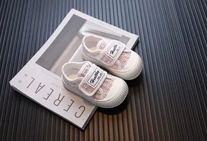 Gros plan de chaussures en toile de tweed rose pour bébé fille avec velcro blanc