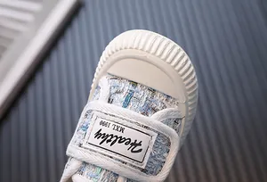 Détail d'une chaussure en toile de tweed pour fille avec embout en caoutchouc blanc
