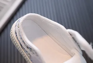 Détail de chaussures en toile blanches pour filles avec bordure en tweed et doublure