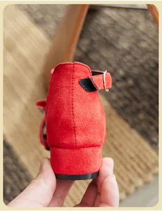 Vista dettagliata del tacco in camoscio rosso e del cinturino di un sandalo da bambina
